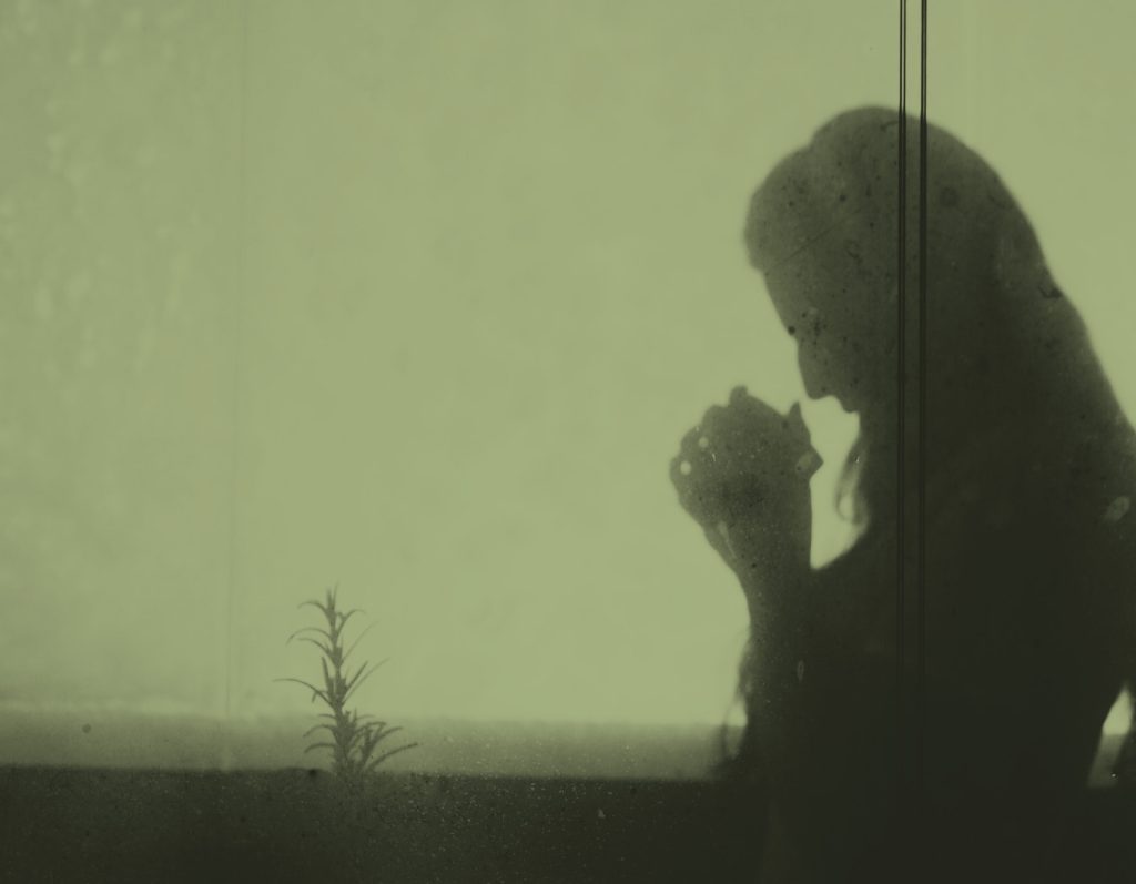 Skugga mot en v&auml;gg av en kvinna som ber