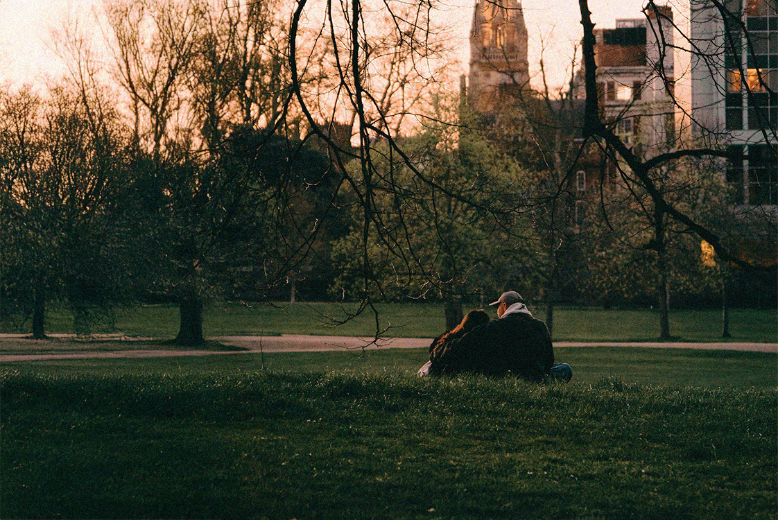 Ett ungt par sitter i en park i solnedgången.